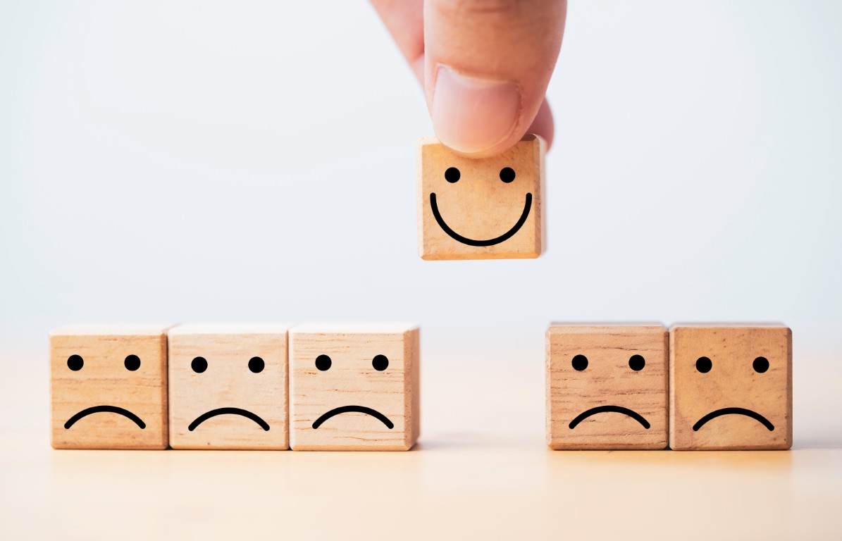 Hand holding Smile face print screen on wooden cube block among